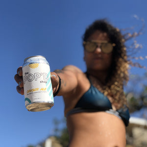 Woman holding can of Ginger Ale at the beach.